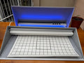 Equipo UV GIPCELTA abierto: barra LED UV encendida y lámina adhesiva cuadriculada